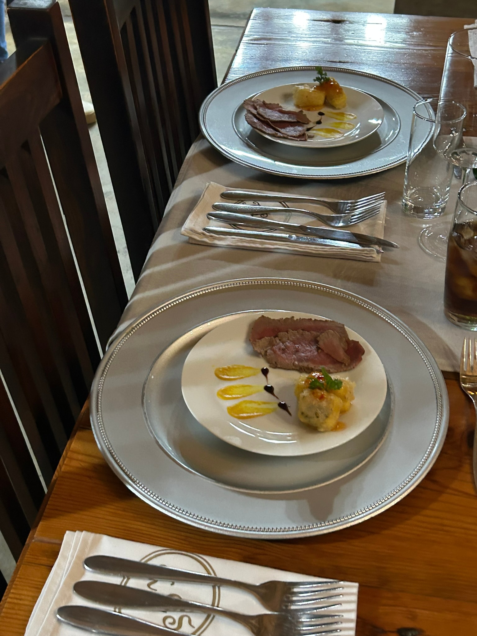 Plated game meat starter with sauce on silver charger