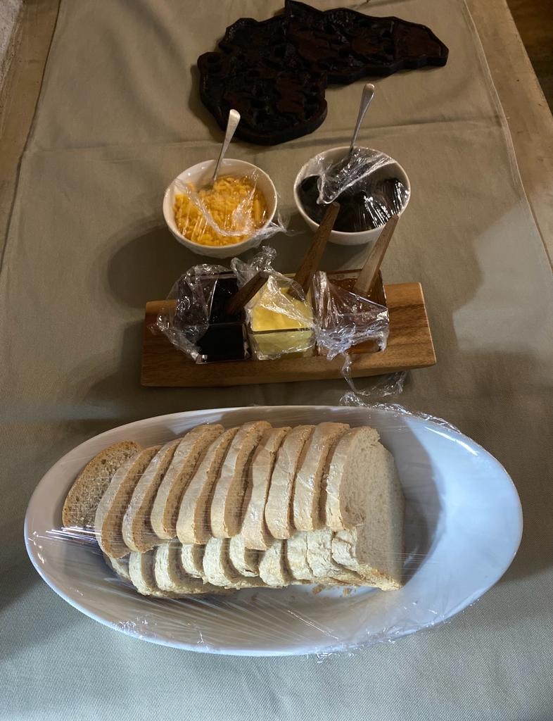 Sliced bread with butter, jam and condiments on table