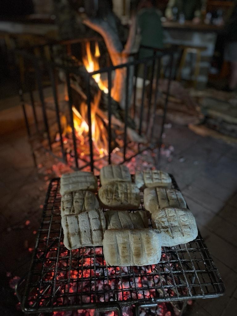 Bread rolls grilling over open fire coals
