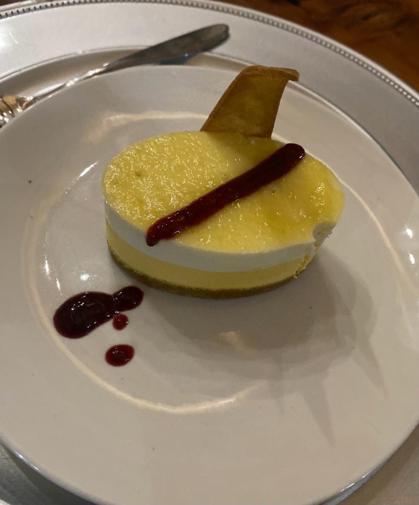 Lemon cheesecake with berry coulis on white plate