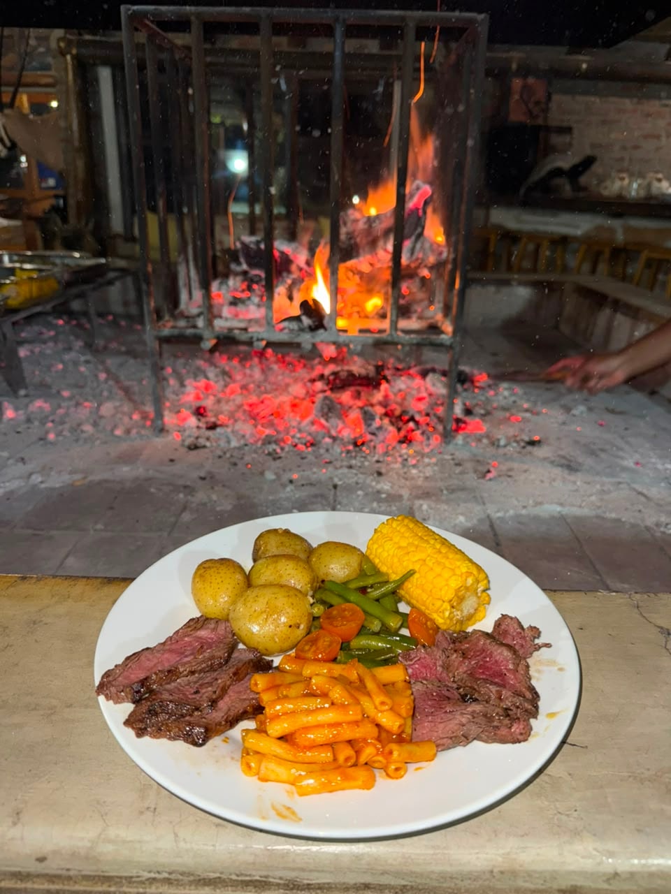Grilled steak with baby potatoes, corn and green beans by the boma fire