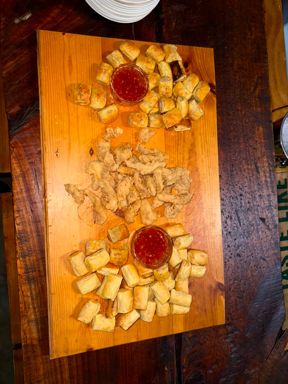 Fried appetizers and mini rolls with sweet chilli dipping sauce on a wooden board